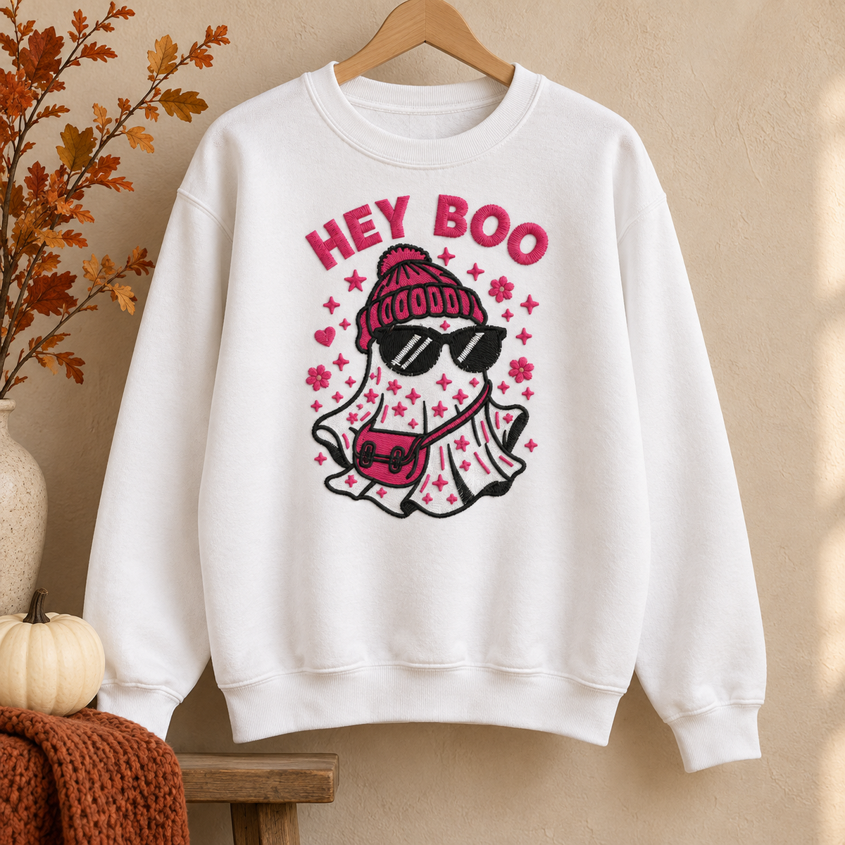 White Hey Boo embroidered Halloween crewneck sweatshirt hanging on a wooden hanger