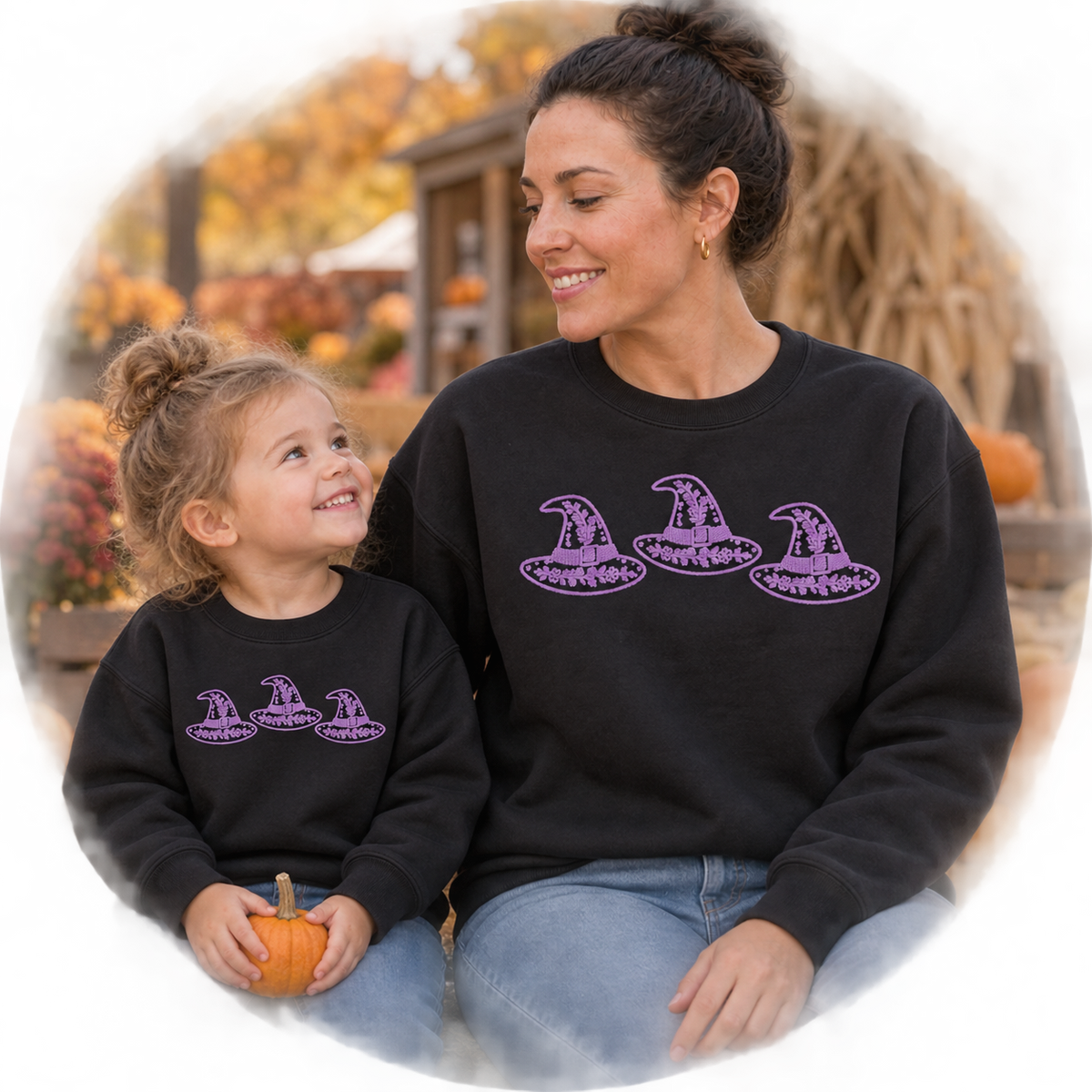 Adult and toddler wearing matching black sweatshirts with lavender witch hat trio embroidery