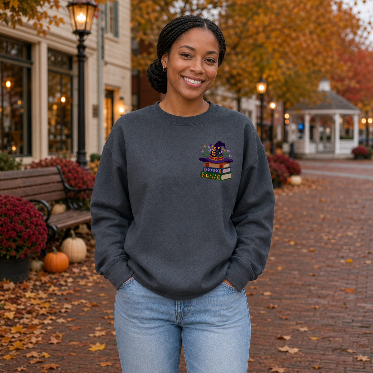 Woman wearing Dark Heather Gildan Softstyle sweatshirt with floral witch hat book stack embroidery