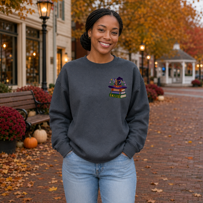 Woman wearing Dark Heather Gildan Softstyle sweatshirt with floral witch hat book stack embroidery