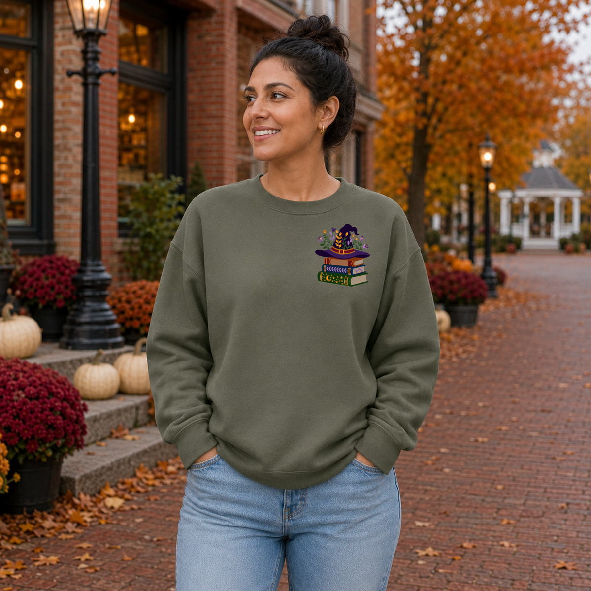 Woman wearing Military Green Gildan Softstyle sweatshirt with small witch hat and books embroidery