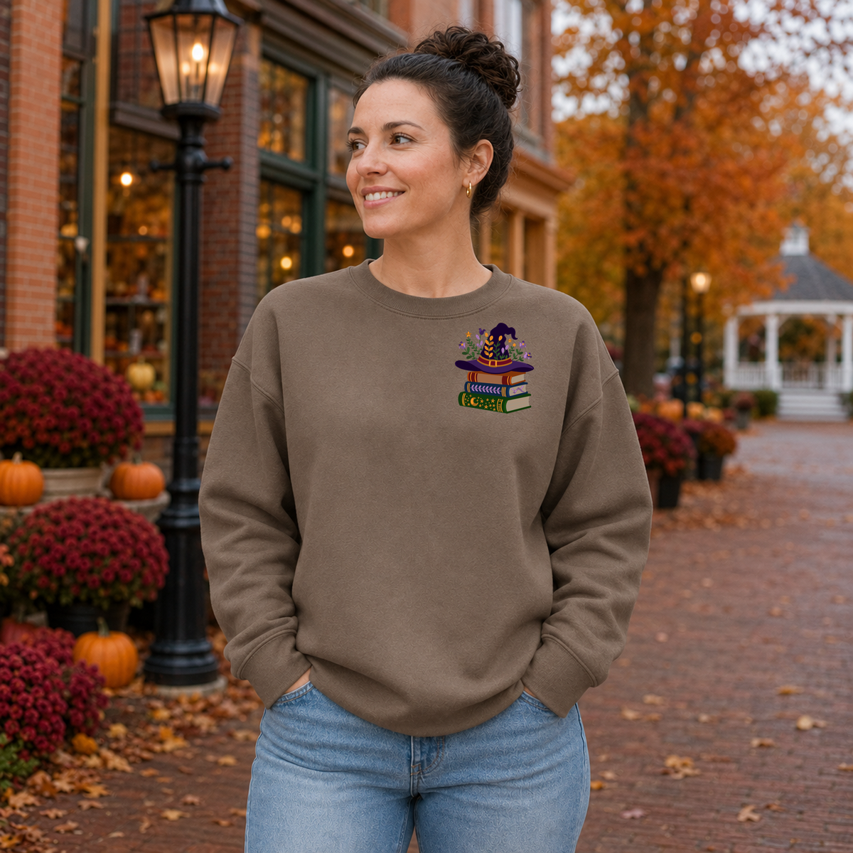 Woman wearing Brown Savanna Gildan Softstyle sweatshirt with left chest witchy book lover embroidery