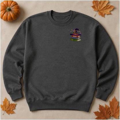 Dark Heather sweatshirt flat lay with embroidered witch hat and colorful book stack
