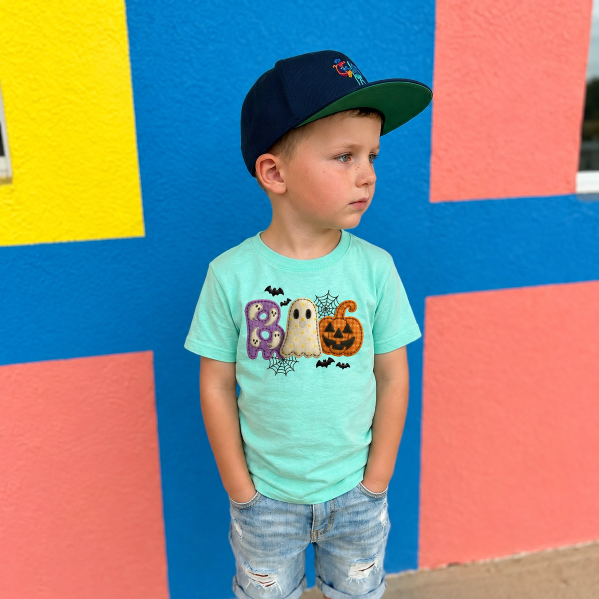 Youth wearing Saltwater LAT BOO Halloween T-shirt with purple ghost, cream ghost, pumpkin, bats and webs